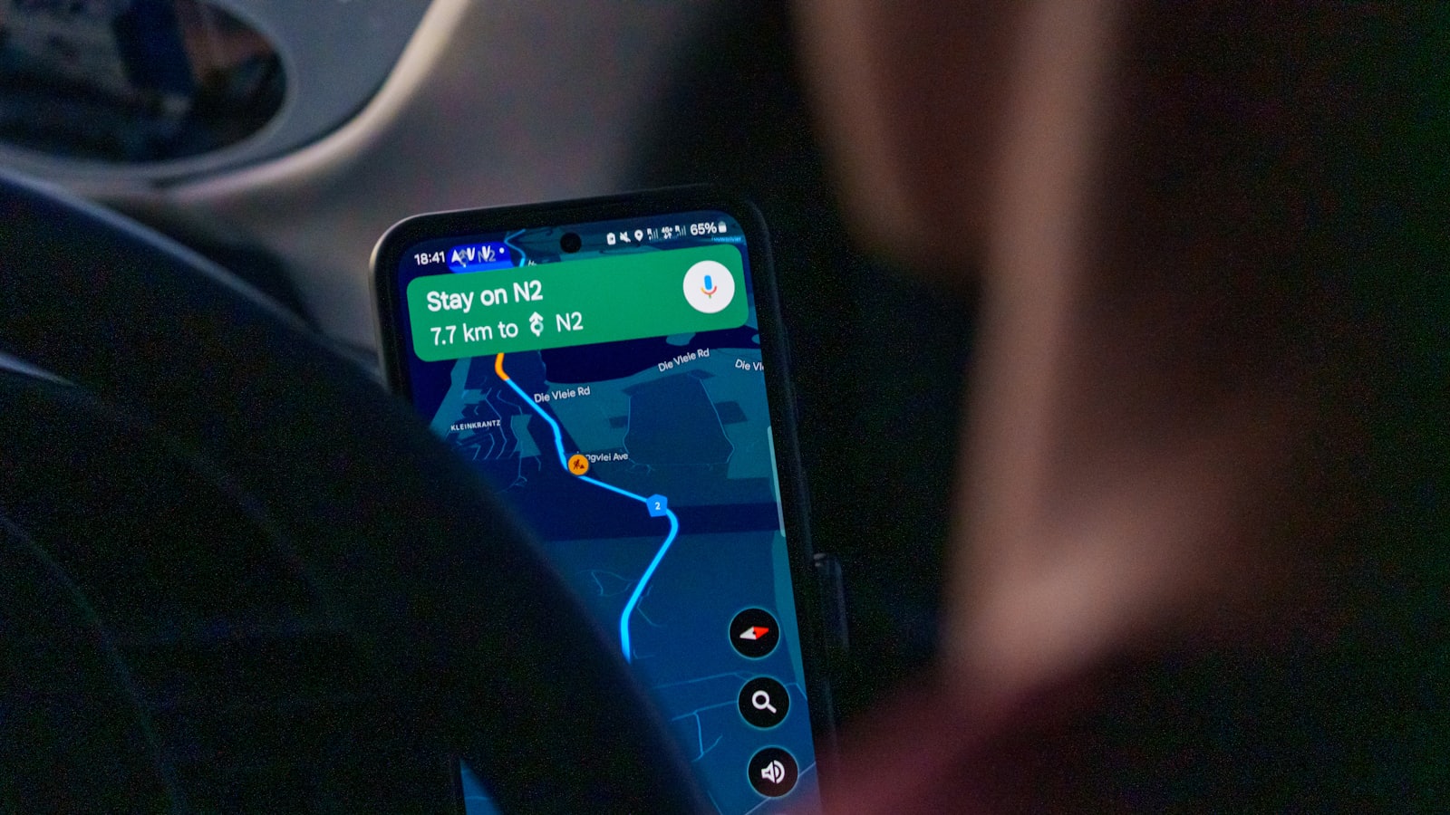 Smartfon w uchwycie samochodowym z uruchomioną nawigacją podczas jazdy